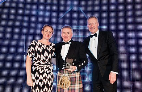 Jane McCarthy, field sales manager for awards sponsor Coca-Cola Enterprises, left, and awards event host Rory Bremner, right, present the Scottish Grocer 2015 Best Soft Drinks Outlet of the Year Award to Roy Williams of United Wholesale Scotland – receiving on behalf of Day-Today Wallyford Supermarket.
