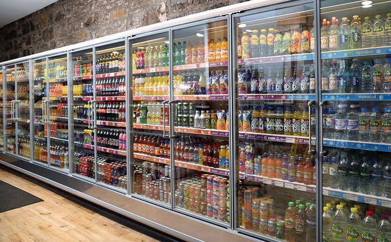 A long bank of glass-fronted chillers runs almost the length of the shop, displaying chilled foods, dairy and soft drinks. At the end of the run are upright freezers containing a range of frozen food. 