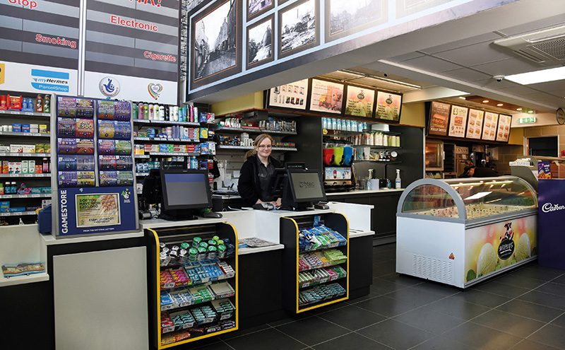 Media screens facing customers at the counter are used to display the latest promotions. Tobacco is stored upstairs, while an illustration of a cigarette gantry is on the wall, with slogans warning against smoking.